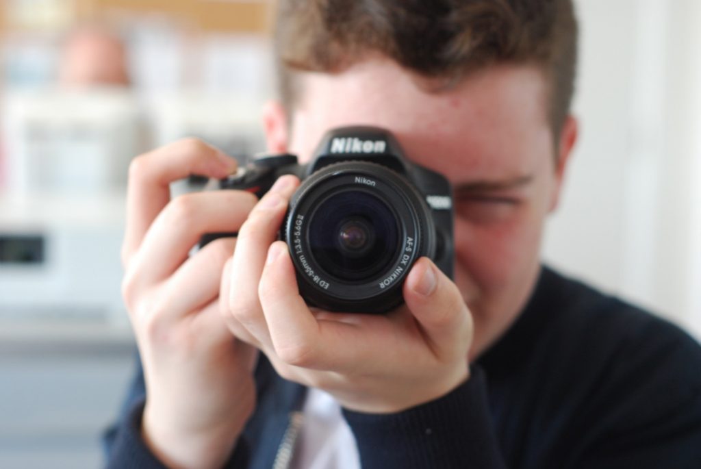 Image shows a young person with a camera from one of our previous workshops