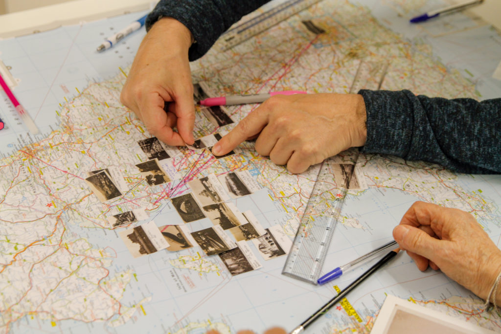 Hands placing small photographs onto printed map