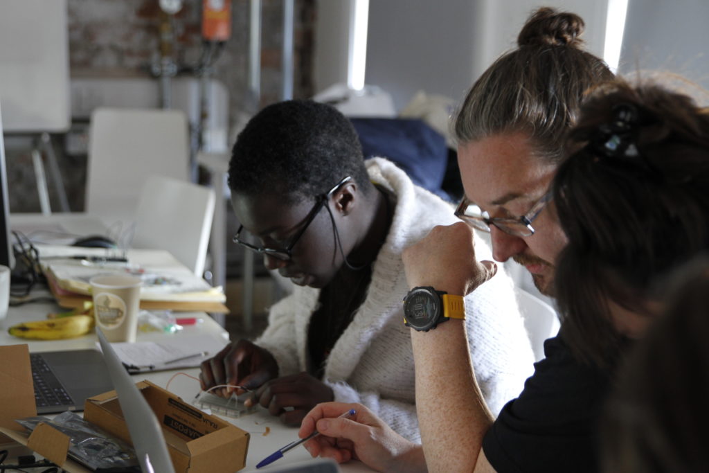 Woman and man using small circuit board on table during workshop.