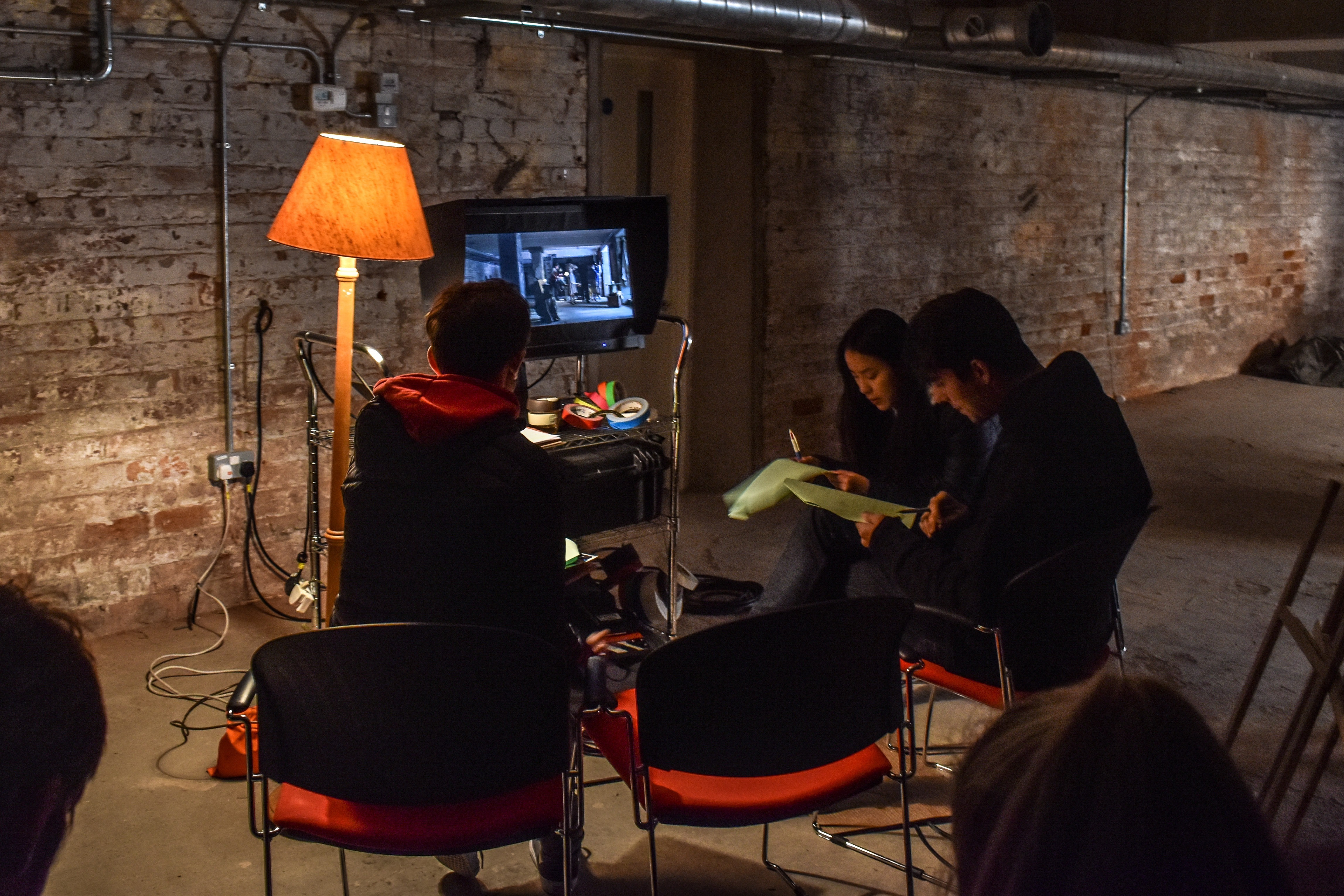 Group of teenagers gather to watch a film clip on a television.