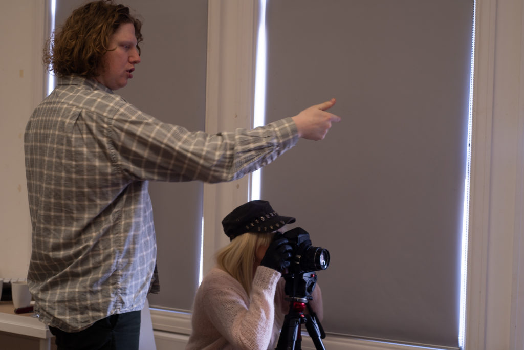 Male tutor advises woman takes photograph on DSLR camera during workshop