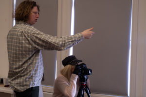 Male tutor advises woman takes photograph on DSLR camera during workshop