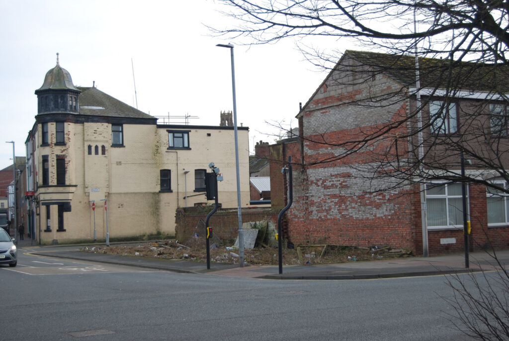 A colour landscape photograph of a street corner. In the middle of the picture is a pedestrian crossing.
