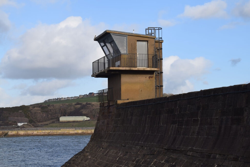 A colour photograph of a sea defence with a watch tower in the middle of the photograph.