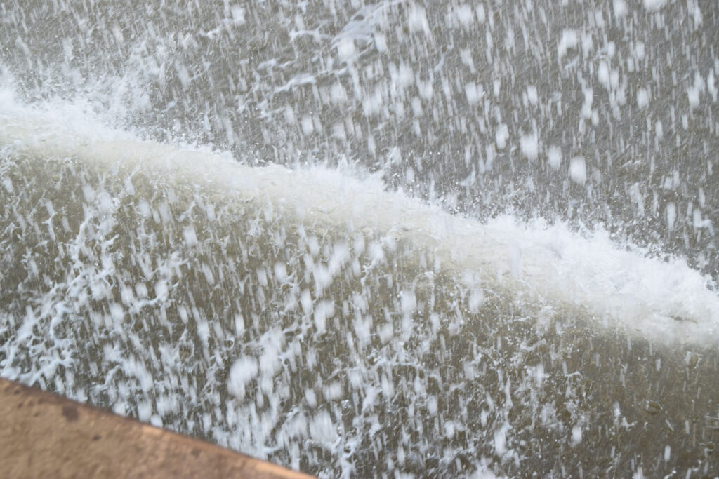 An abstract colour photograph of the sea hitting against the wall and the spray from the water.